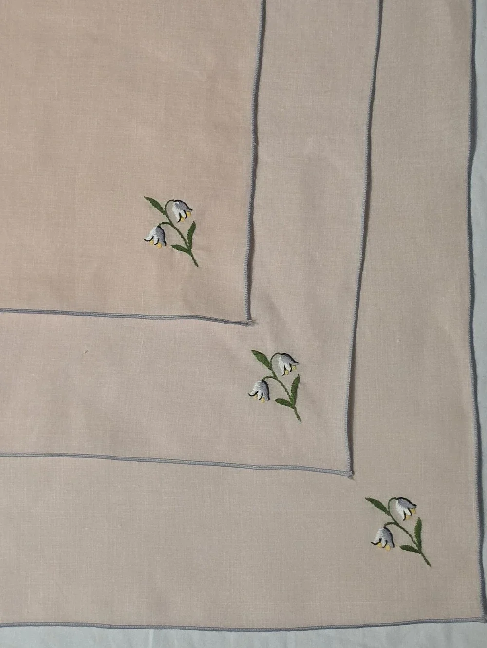 THREE LARGE PINK LINEN NAPKINS WITH EMBRIODERED LILLY OF THE VALLEY ACCENT